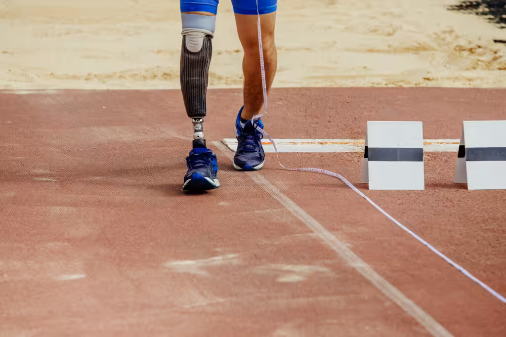 A man with prosthetic leg is running on a playing field