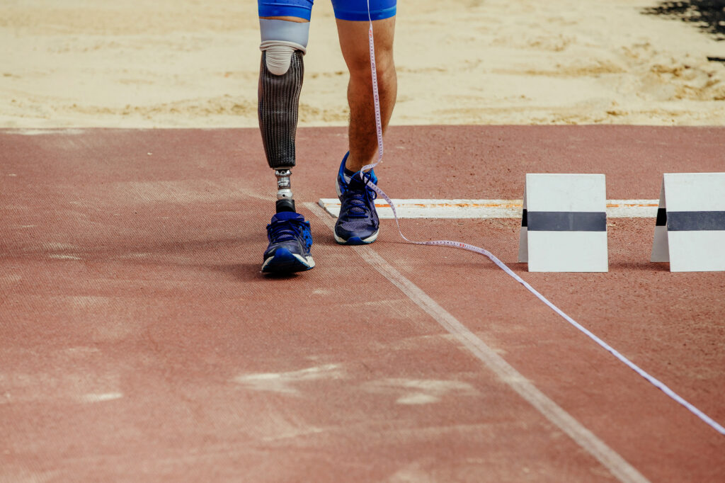 A man with prosthetic leg is running on a playing field