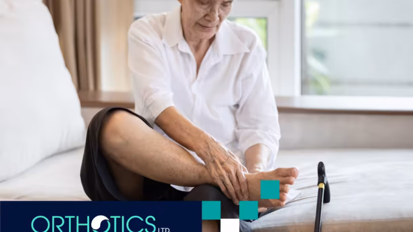 An elderly person sitting on a bed holding her foot