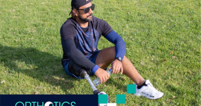 An amputee wearing prosthetics sitting on a grass ooutdoors