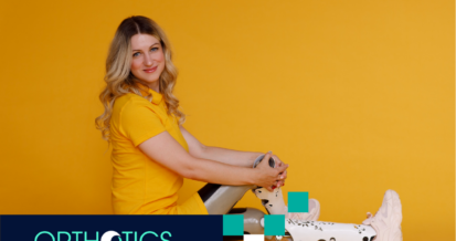 A girl wearing prosthetic cosmetic cover sitting on a floor in front of a yellow backdrop