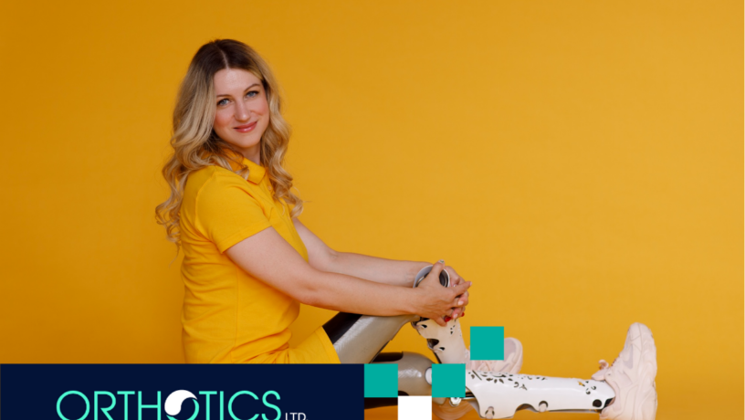 A girl wearing prosthetic cosmetic cover sitting on a floor in front of a yellow backdrop
