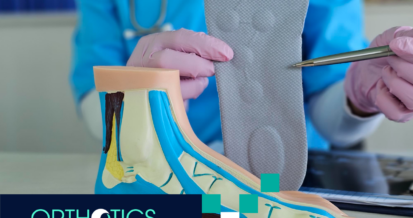 A medical assistant holding an orthotic insole, with a model of a foot on a table