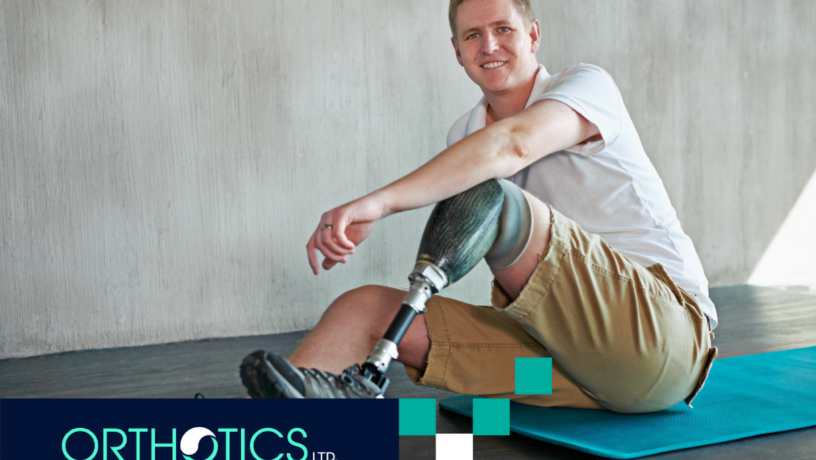 An amputee wearing prosthetics sitting on a mat