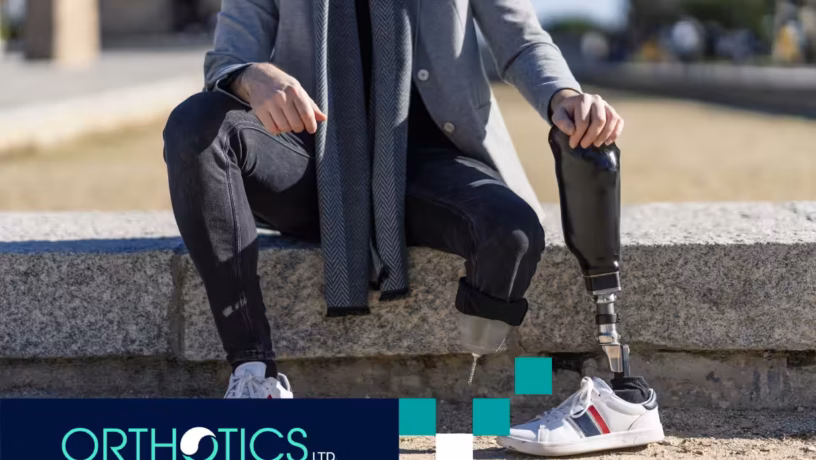 An amputee sitting outdoors, holding a prosthesis
