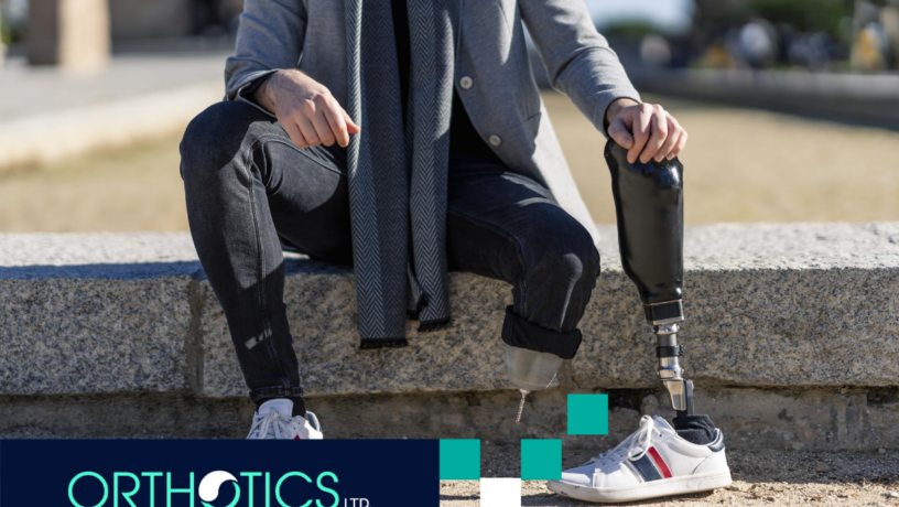 An amputee sitting outdoors, holding a prosthesis