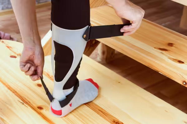 A person adjusting his ankle foot orthosis
